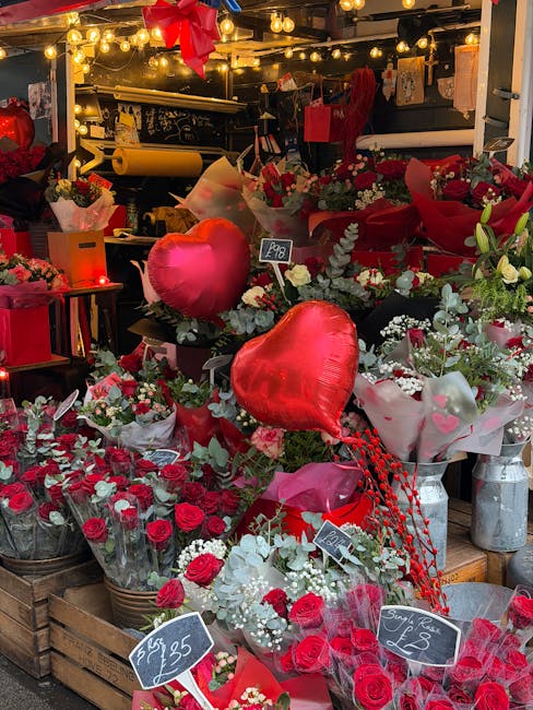 A vibrant floral display at Brondesbury Florist, showcasing a variety of fresh flowers arranged in bouquets and gift sets. The arrangement includes red roses, white baby's breath, and greenery, all be